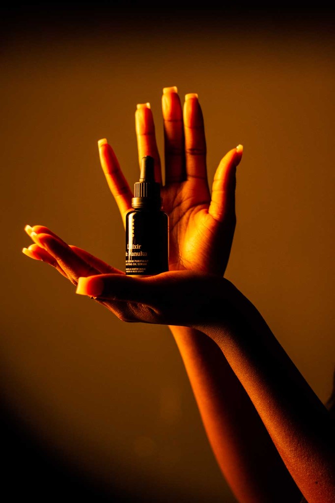 Hand holding a founder-led serum bottle in warm light