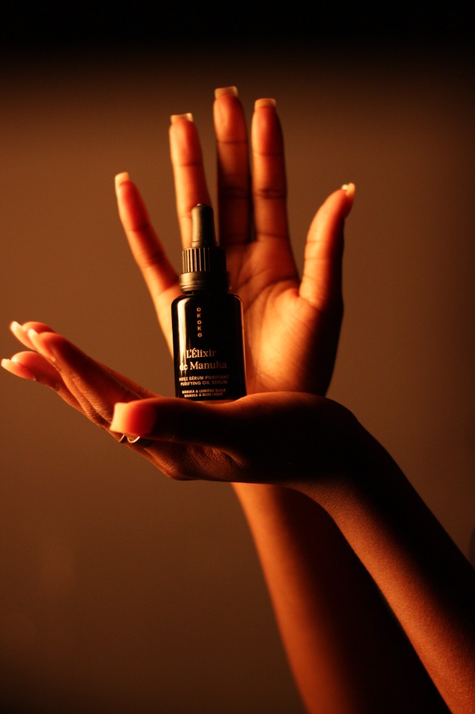 Hands presenting OKOKO purifying oil serum dropper bottle